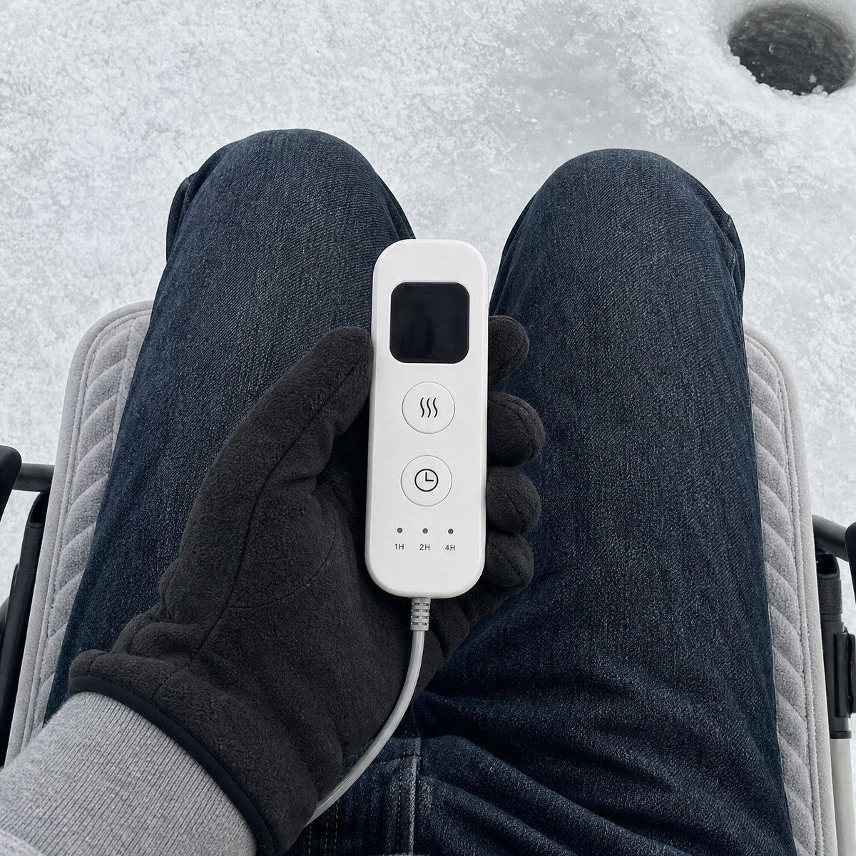 Gloved hand using the WarmCast remote on the ice